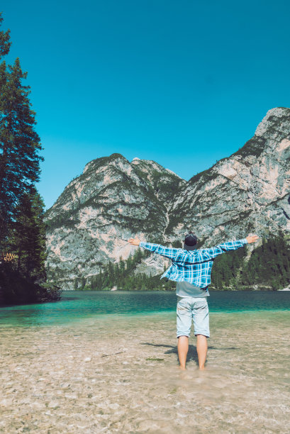 男人举起双手，站在湖山的背景上图片下载