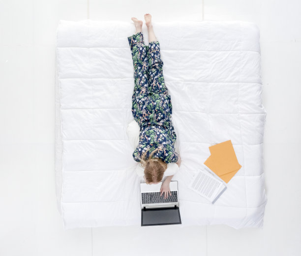 上图/全身/一个20-29岁的成年美丽的白人女性/年轻女性躺在卧室的白色背景穿着睡衣谁是工作到很晚谁是工作/感官/诱惑图片下载