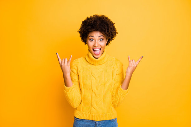 照片漂亮的黑皮肤的女士在摇滚音乐会唱最喜欢的热门歌曲穿暖和的针织套衫孤立的黄色背景图片下载