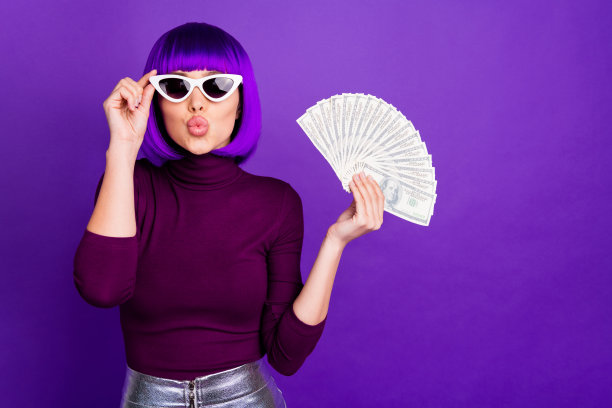 照片时尚的女士抱着美国雄鹿的扇子送飞吻穿时髦的服装孤立的紫色背景图片下载