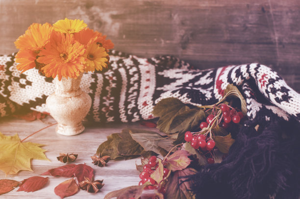 漂亮舒适的静物，黄色的干叶，荚蒾，围巾和橙色的花，躺在复古风格的木桌上图片下载