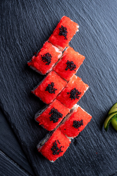 一套寿司卷，奶油芝士，米饭和鲑鱼在黑色的木板装饰生姜和芥末在深色的木制背景。日本料理。食物的照片背景。俯视图图片下载