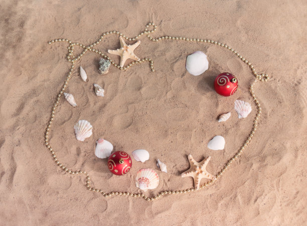 沙滩上的圣诞球、珠子、海星和贝壳做成的框架。庆祝圣诞节和新年。图片下载