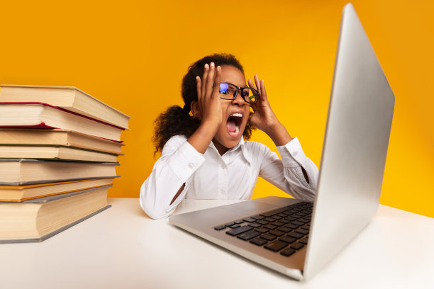 非洲女学生在黄色演播室背景下对着笔记本电脑尖叫图片下载