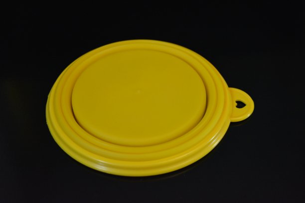 黄色折叠多功能橡胶板，一个碗与塑料边缘在黑色光滑表面。图片下载
