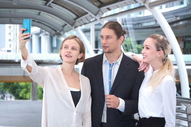 一群快乐的商务人士在地铁站的中央商务区见面自拍。图片下载