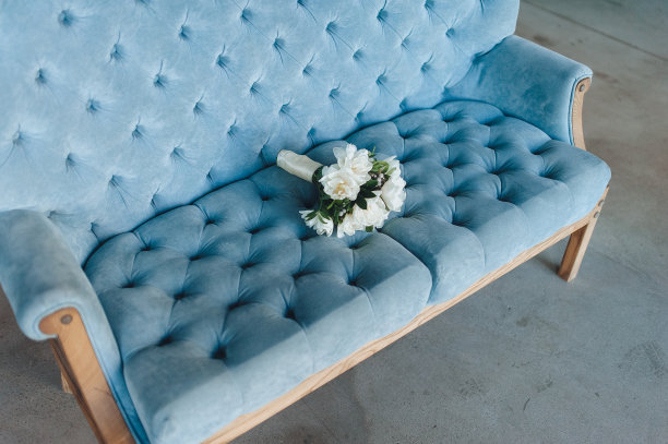 在一间现代化的工作室里，蓝色的沙发上放着一束新娘用的白色鼻孔花。婚礼的细节。图片下载