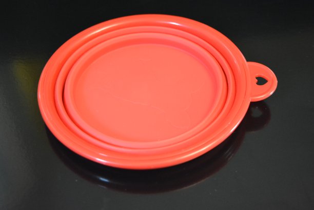 红色折叠多功能橡胶板，一个碗与塑料边缘在黑色光滑表面。图片下载