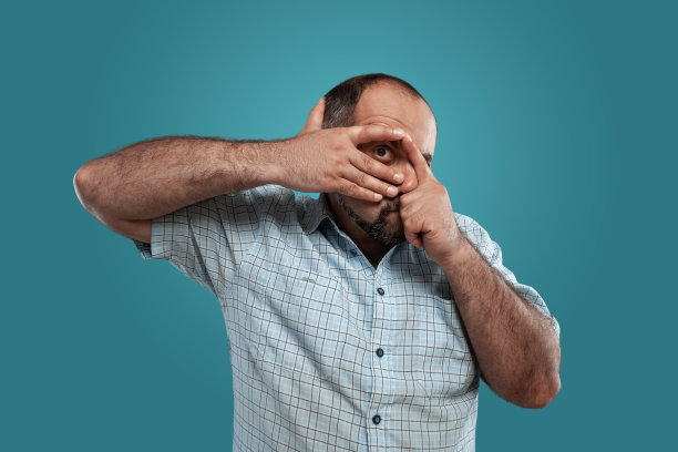 近距离的肖像，一个深色的中年男子胡子，穿着浅格子衬衫和摆姿势的蓝色背景图片下载