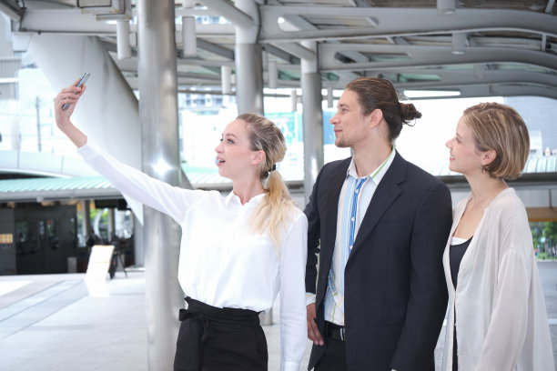 一群快乐的商务人士在地铁站的中央商务区见面自拍。图片下载