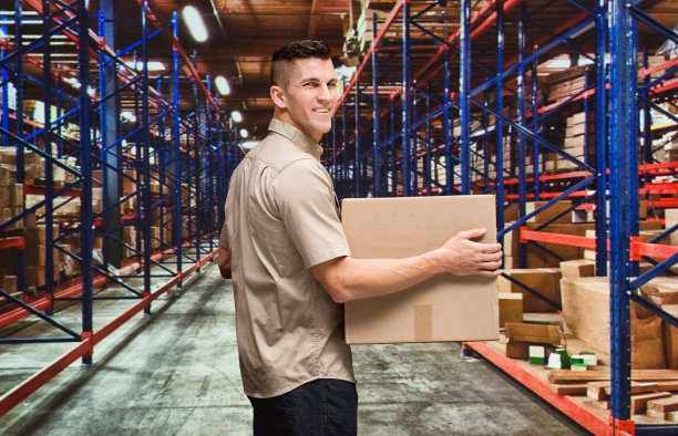 一个男人/一个人/腰部以上/后视图/背面/看镜头的30-39岁的成年人英俊的人棕色头发/短发高加索男性/年轻男子经理/体力工人站在商品前谁是交付图片下载