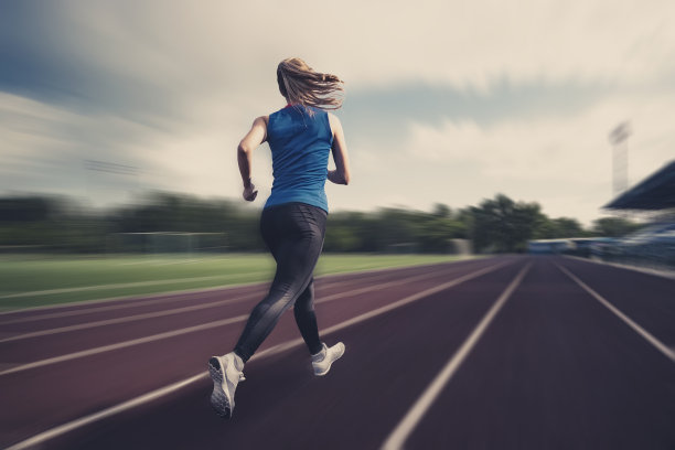 模糊的观点上的跑步女孩在田径比赛。作为背景。田径场上的运动员。图片下载