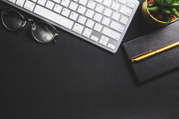 办公桌旁有电脑、用品和植物。图片下载