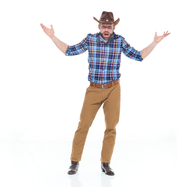 全身长/一人独/一人30-39岁的成年人英俊的人白人男性/年轻的牛仔男子站在白色背景下穿着牛仔靴/牛仔帽/帽子谁是困惑/不确定图片下载