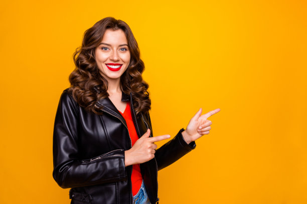 女士的照片与惊人的红色口红表明手指空在低价格穿皮夹克孤立的黄色背景图片下载