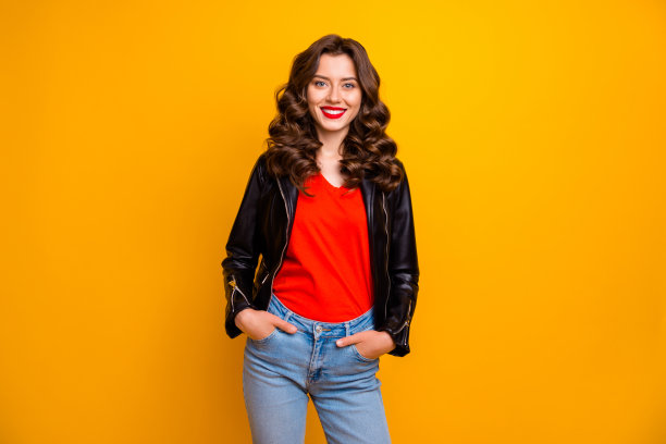 照片上的女士与惊人的笑容和红色口红去派对穿皮夹克和牛仔裤孤立的黄色背景图片下载