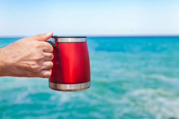 海滩上的红色野营咖啡杯保温瓶图片下载