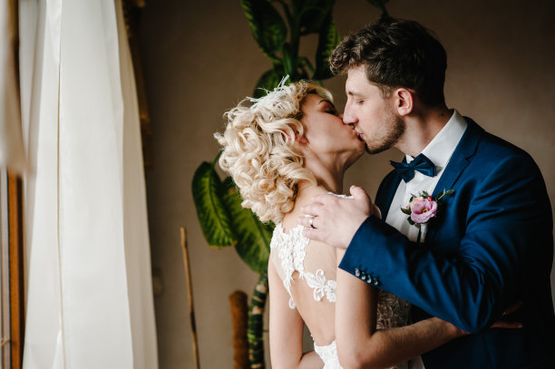 新娘和新郎。第一次会议。新婚夫妇站在室内靠窗的地方。图片下载