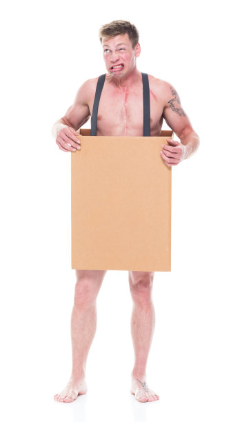 正面图片/全身/一个20-29岁的白人男性/年轻男子站在白色背景前，穿着背带，绝望/饥饿/贫穷/赤上身/做鬼脸/幽默和乞讨/图片下载