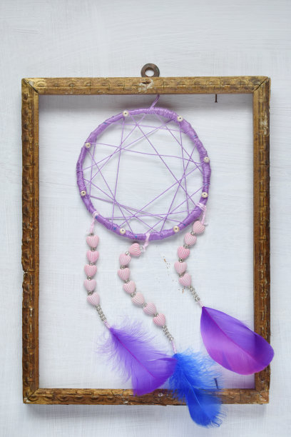 白色背景上的紫色捕梦网。卧室的捕梦网装饰配件，特写照片。车间，爱好，手工艺，创意概念。图片下载