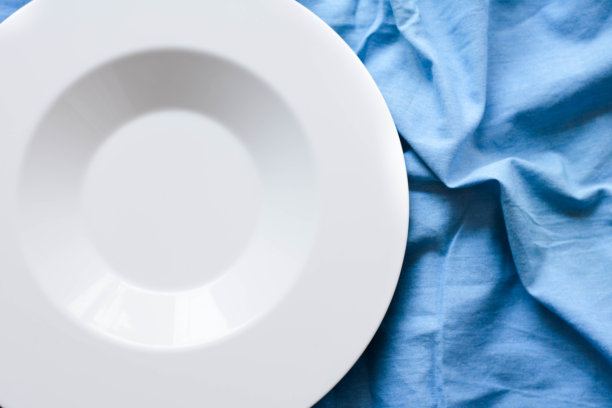 浅蓝色桌布上的白色盘子的俯视图图片下载