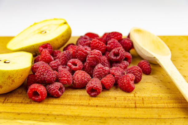 红覆盆子和梨放在砧板上。图片下载