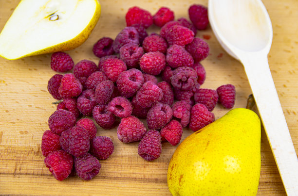 红覆盆子和梨放在砧板上。图片下载