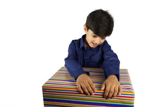 盒子里是什么?一个快乐的小印度亚洲男孩拿着礼物，看着它微笑，脸朝下在幸福股票照片孤立的白色背景图片下载