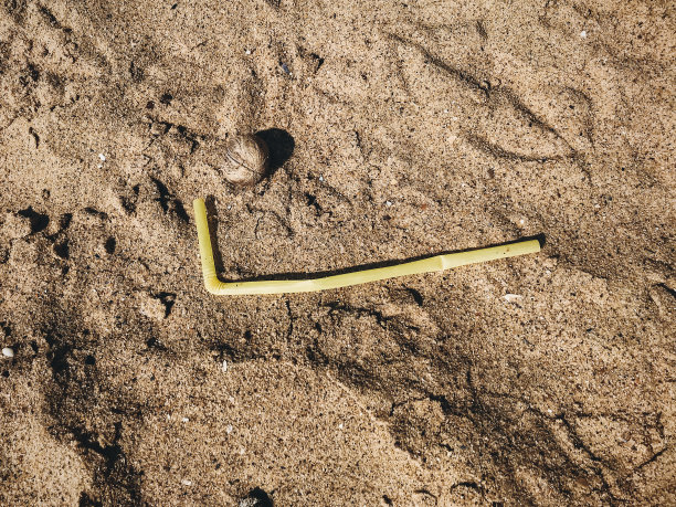 沙子里的一次性塑料吸管，海滩上的海洋垃圾。海滩上的塑料污染。停止塑料污染。垃圾在海岸。垃圾的灾难。“零浪费”图片下载