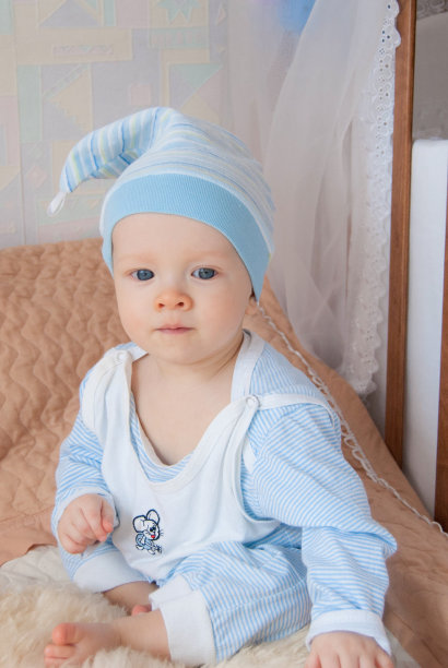 滑稽可爱的小男孩戴着一顶侏儒帽躺在床上图片下载