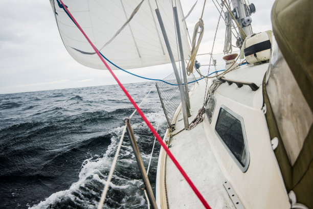 白色游艇在阴天航行。从甲板到船头、桅杆和帆的视野。挪威图片下载