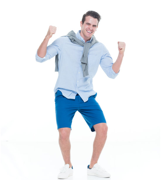 一人/一人/全身/ 20-29岁的成年英俊的人白人男性/年轻男子站在/弯腰在白色背景下穿着短裤/卷起袖子/毛衣/帆布鞋/酷的态度/膝盖图片下载