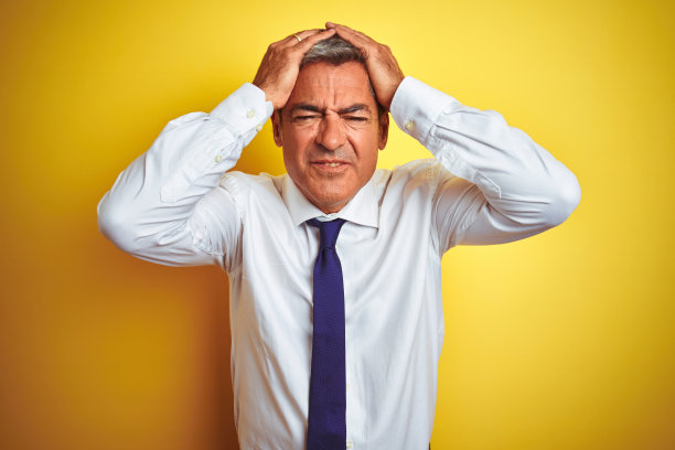 英俊的中年商人站在孤立的黄色背景遭受头痛绝望和压力，因为疼痛和偏头痛。手放在头上。图片下载