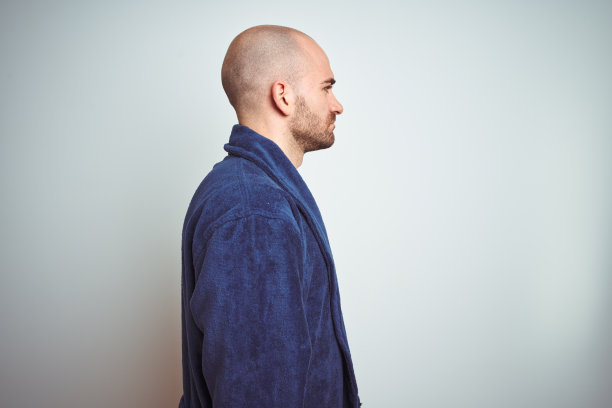 年轻人穿着蓝色浴衣，轻松的生活方式在孤立的背景看向一边，放松的轮廓姿势与自然的脸与自信的微笑。图片下载