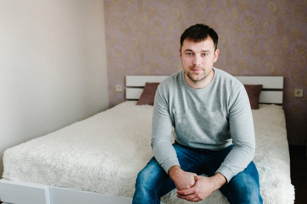 一个男人坐在家里的床上。快乐的爸爸和丈夫。等待假期和家人。图片下载