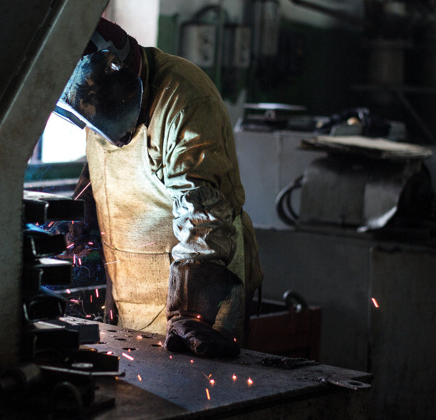 焊工在工厂的一个焊接面罩中焊接金属件，焊接和电火花、焊条、车间图片下载