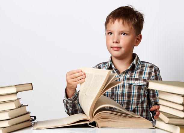 一个男生坐在课桌前翻着书。图片下载