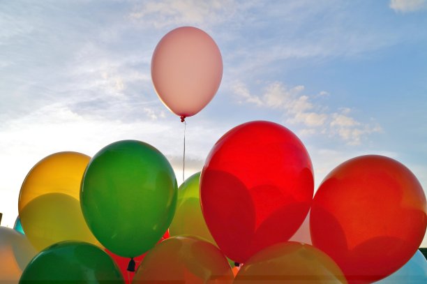 混合彩色气球在蓝天背景和阳光透过云层。蓝天上的装饰气球。29、夏天和情人概念相爱，新婚度蜜月。图片下载