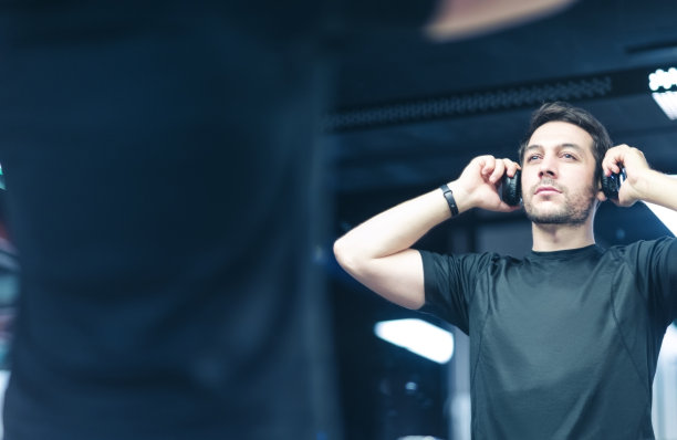 英俊的年轻人在健身房边听音乐边看镜子图片下载