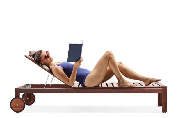 年轻女性穿着泳衣躺在躺椅上看书图片下载