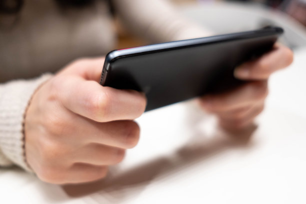 年轻女性汉斯与黑色智能手机观看屏幕。图片下载