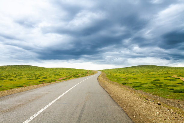 道路之间风景如画的绿色草地，映衬着蒙古的天空。图片下载