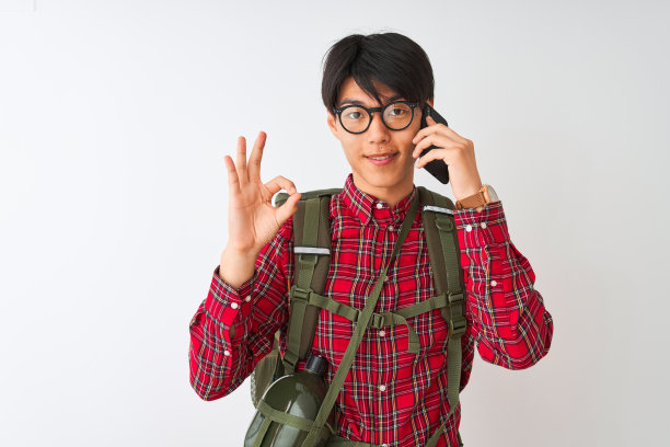 中国徒步男子戴着水壶，在孤立的白色背景下用智能手机说话，用手指做ok手势，很好的象征图片下载