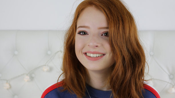 照片中的14 / 15岁红头发、皮肤苍白、长着雀斑的少女坐在卧室里看着镜头，神情轻松，微笑着做鬼脸图片下载