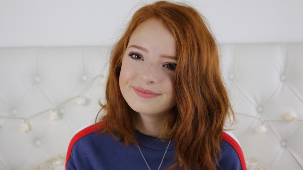 照片中的14 / 15岁红头发、皮肤苍白、长着雀斑的少女坐在卧室里看着镜头，神情轻松，微笑着做鬼脸图片下载