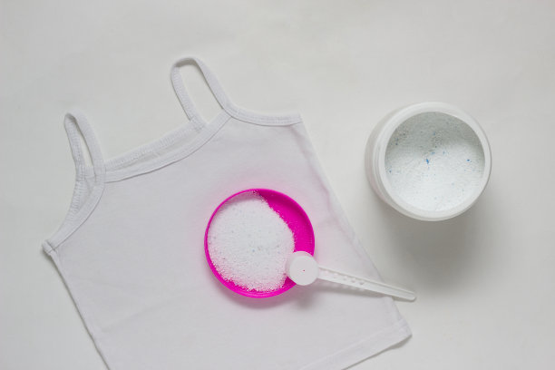白色儿童t恤上装有去污剂的容器，白色背景，漂白剂，增白剂图片下载