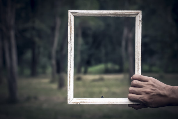男子手持破旧别致的白色复古木框，模糊了绿色自然的概念理念背景图片下载