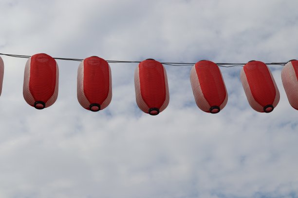 红白相间的日本纸灯笼挂在绳上，映衬着天空的白云图片下载