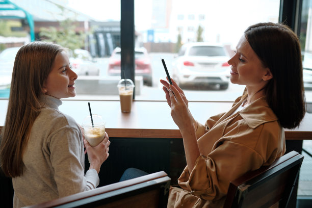 年轻漂亮的女人用手机拍她女儿喝酒的照片图片下载