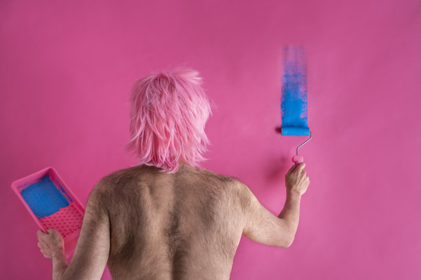 滑稽的毛背男人粉红色翅膀画墙在蓝色图片下载